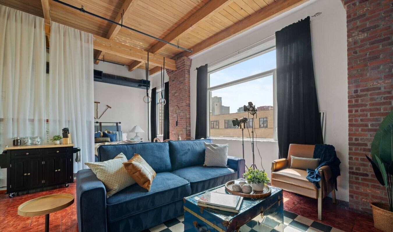 Cozy open-concept studio with stylish decor, exposed beams, and a sofa bed for extra guests.