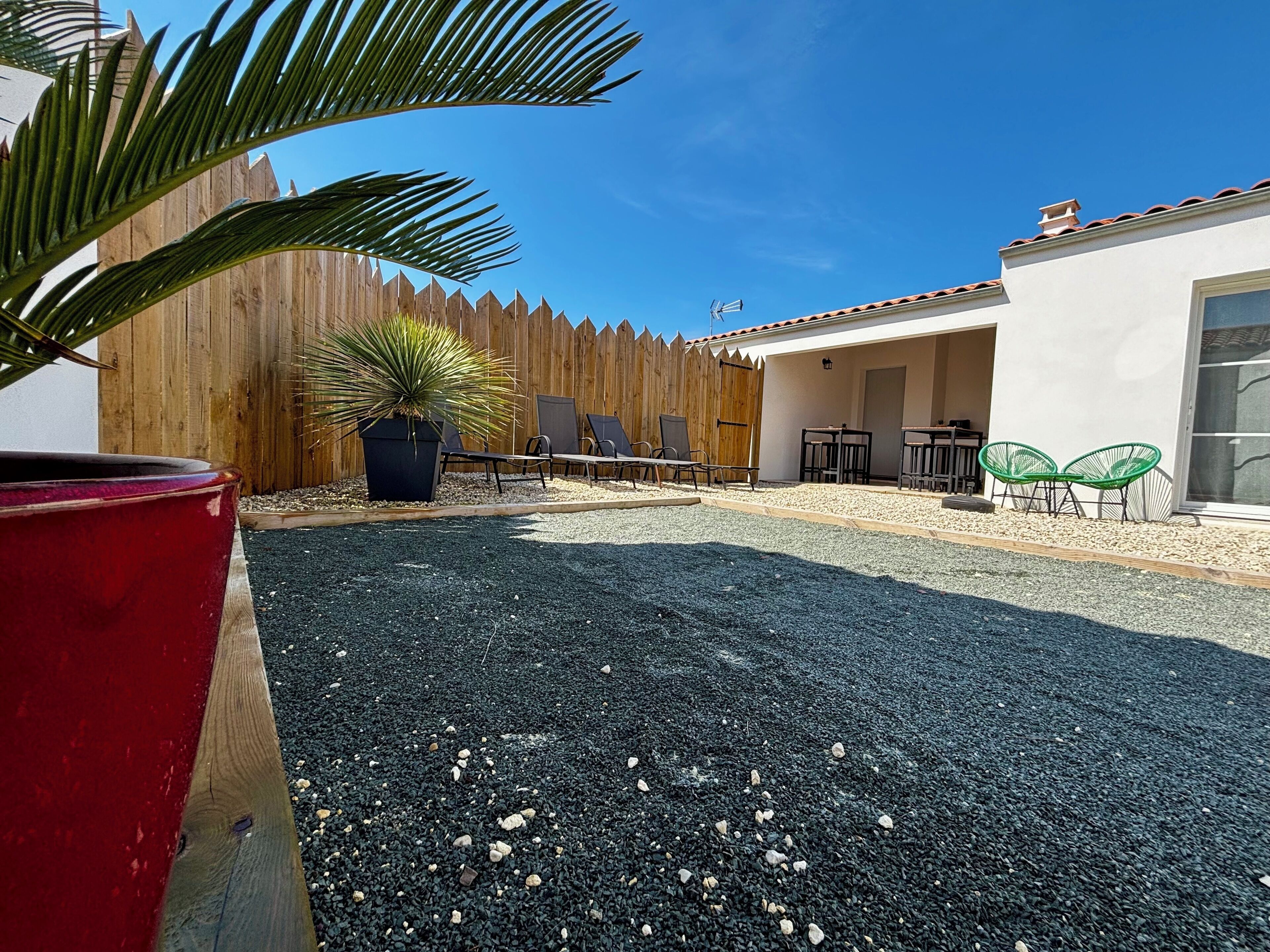 A patio area with a wooden fence, outdoor furniture, and a potted plant.