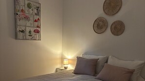 A bedroom with a bed, bedside table, lamp, and decorative wall art.