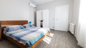 A bedroom with a wooden bed, a wardrobe, a radiator, and a white door. - Le Olive House by Wonderful Italy (Sanremo)