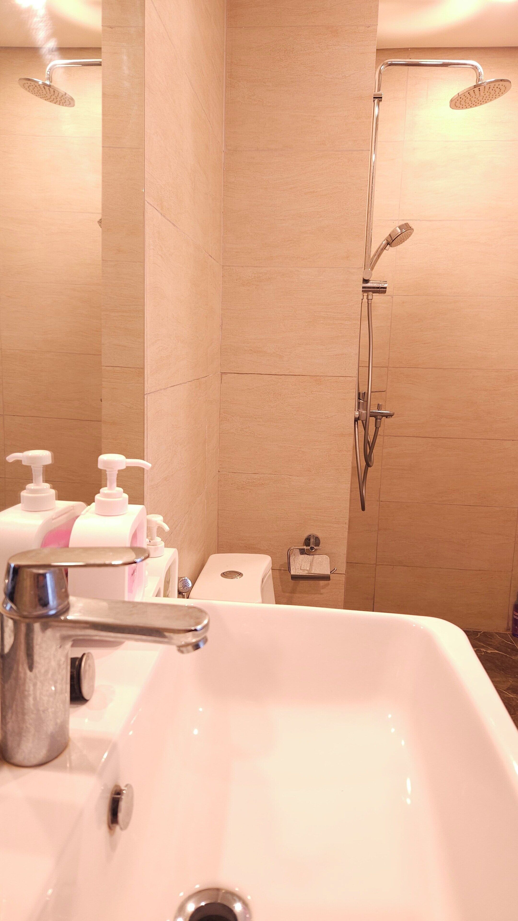 Un baño con lavamanos, dos cabinas de ducha y un inodoro.