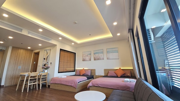 A modern hotel room with two beds, a dining area, and a large window. - FLC Sea Tower Quy Nhon (Quy Nhon Nam)