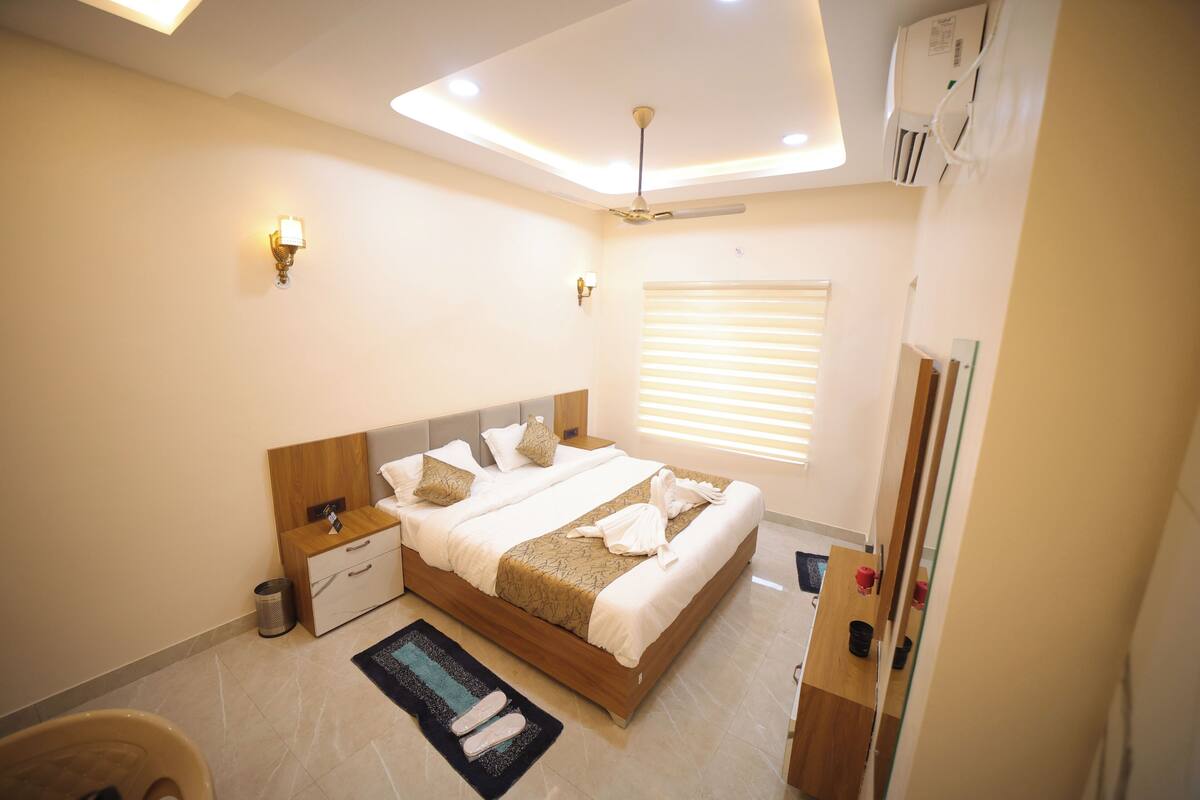 Un dormitorio moderno con cama, mesitas de noche, lámpara de noche, ventilador de techo y ventana con persianas.