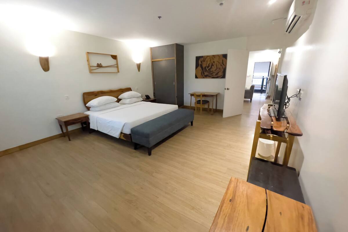 A bedroom with a bed, bedside tables, a desk, and a chair.