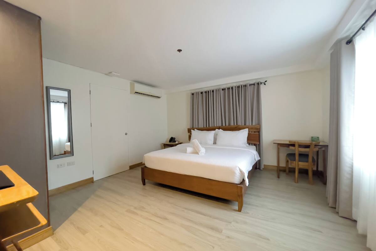 A hotel room with a wooden bed, a desk, and a chair.