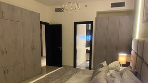 A bedroom with a large bed, grey wardrobe, and a bedside lamp.