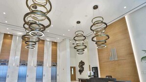 A modern lobby with a reception desk, elevators, and a bench.