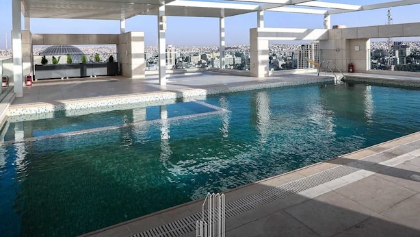 A rooftop pool with a clear view of the cityscape, a covered seating area, and a fire extinguisher.