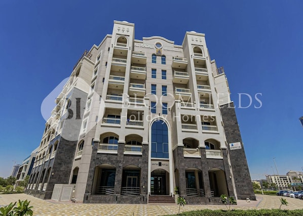 A multi-story hotel with a central entrance, balconies, and a tiled courtyard. - Bloomfields Stylish Stu Burj View Arjan  (Dubai)
