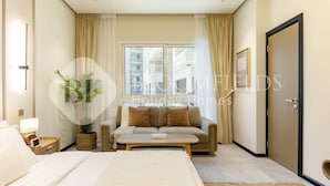 Een moderne hotelkamer met een bed, een bank, een klein tafeltje en een potplant.