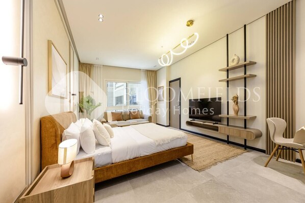 A modern bedroom with a large bed, a TV, and a minimalist decor. - Bloomfields Stylish Stu Burj View Arjan  (Dubai)