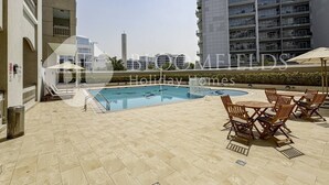 A rooftop pool area with lounge chairs and a swimming pool. - Bloomfields Stylish Stu Burj View Arjan  (Dubai)