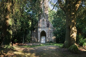 A stone church with an arched entrance, surrounded by trees. - Rental for 2 people, 7 km from Louvigné-du-Désert (35420) (Monthault)