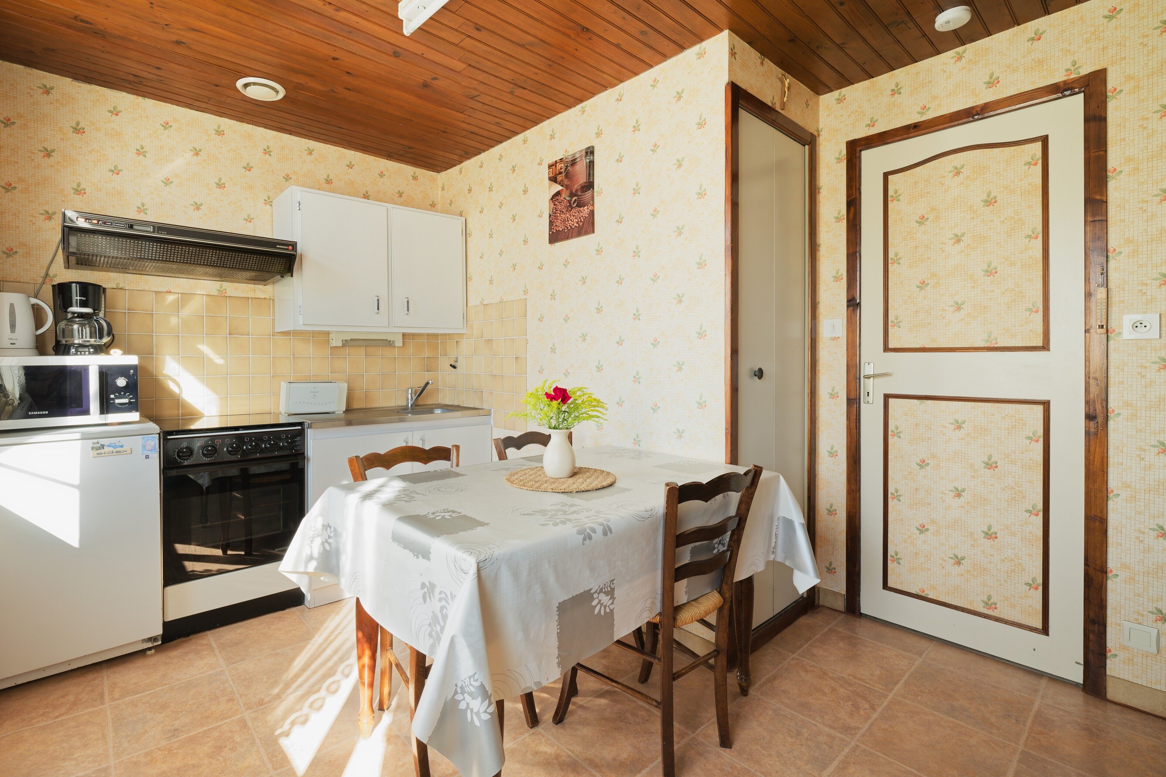 A compact kitchen with a dining table, a coffee maker, a microwave, and an oven.
