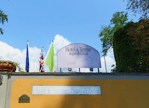 A sign for Hotel & Terme Bagni di Lucca with flags in the background.