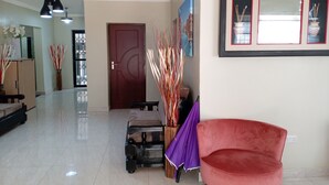 A spacious living area with a red chair, a sofa, and a coffee table. There are two pendant lights, a door, and a framed picture on the wall. - K-View Boutique Hotel (Mzuzu)