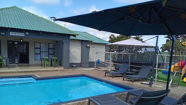 A swimming pool with lounge chairs, a shaded area, and a restaurant named Chilanga Restaurant. - K-View Boutique Hotel (Mzuzu)