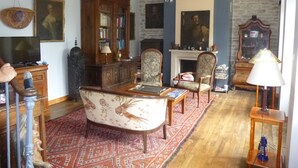 A traditional living room with a fireplace, wooden furniture, and a red patterned rug.