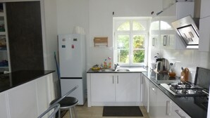 A modern kitchen with white cabinets, a black countertop, a stainless steel stove, and a window providing natural light.