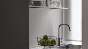 A modern kitchen with white cabinetry, a built-in sink, and a fruit basket on the countertop. - Ruggero City View apartment by Wonderful Italy (Palermo)
