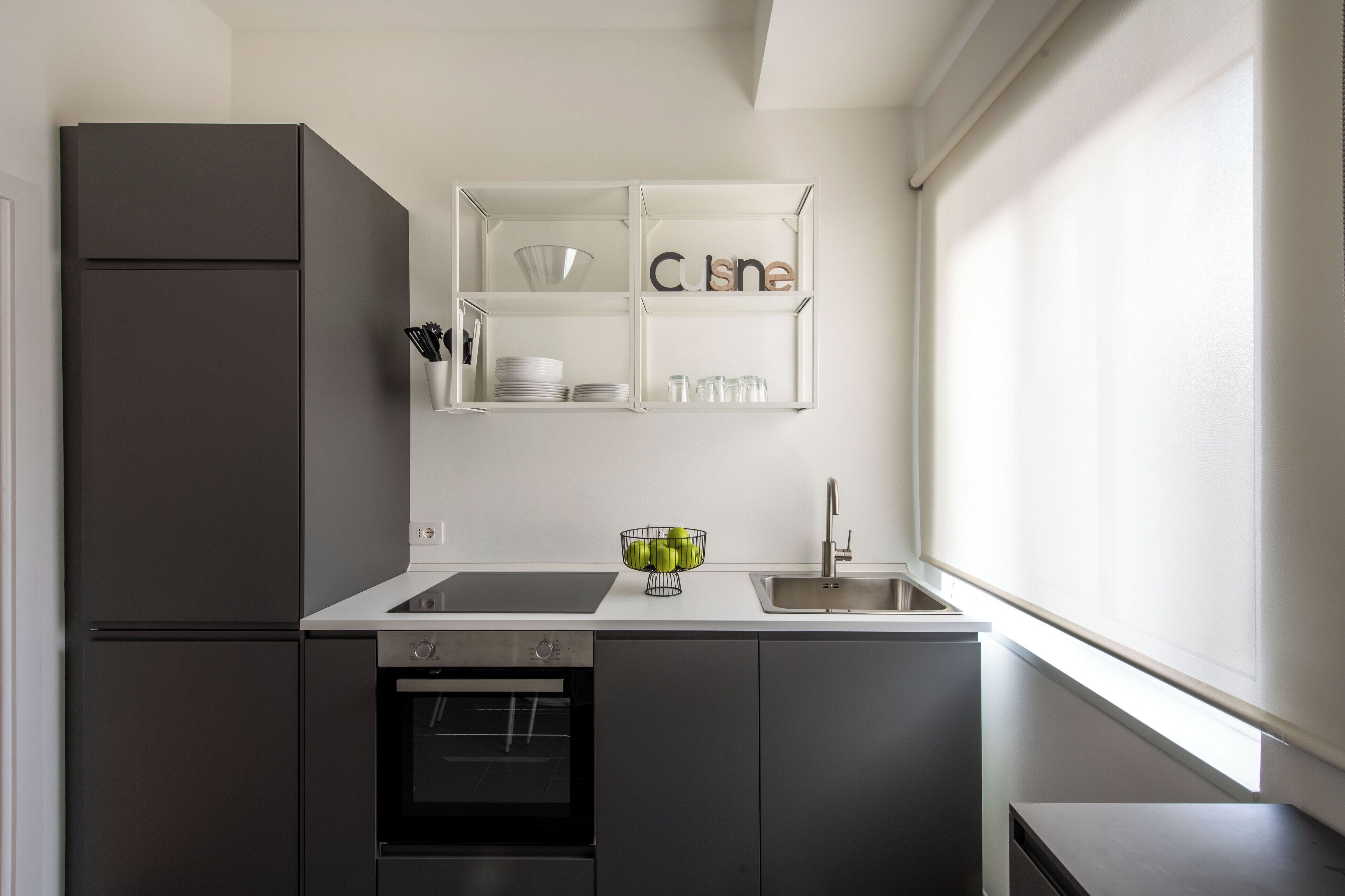 A modern kitchen with a built-in oven, a sink, and a window.