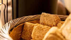 A basket filled with textured food items, possibly bread or similar products, in a setting with a dark background and metallic elements.