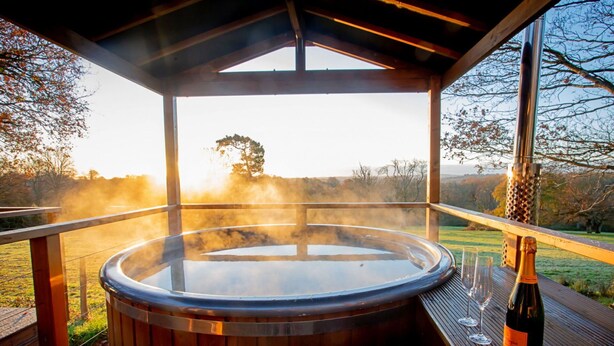 Ein Whirlpool mit Holzterrasse und Glaskonstruktion, umgeben von einer Holzpergola.