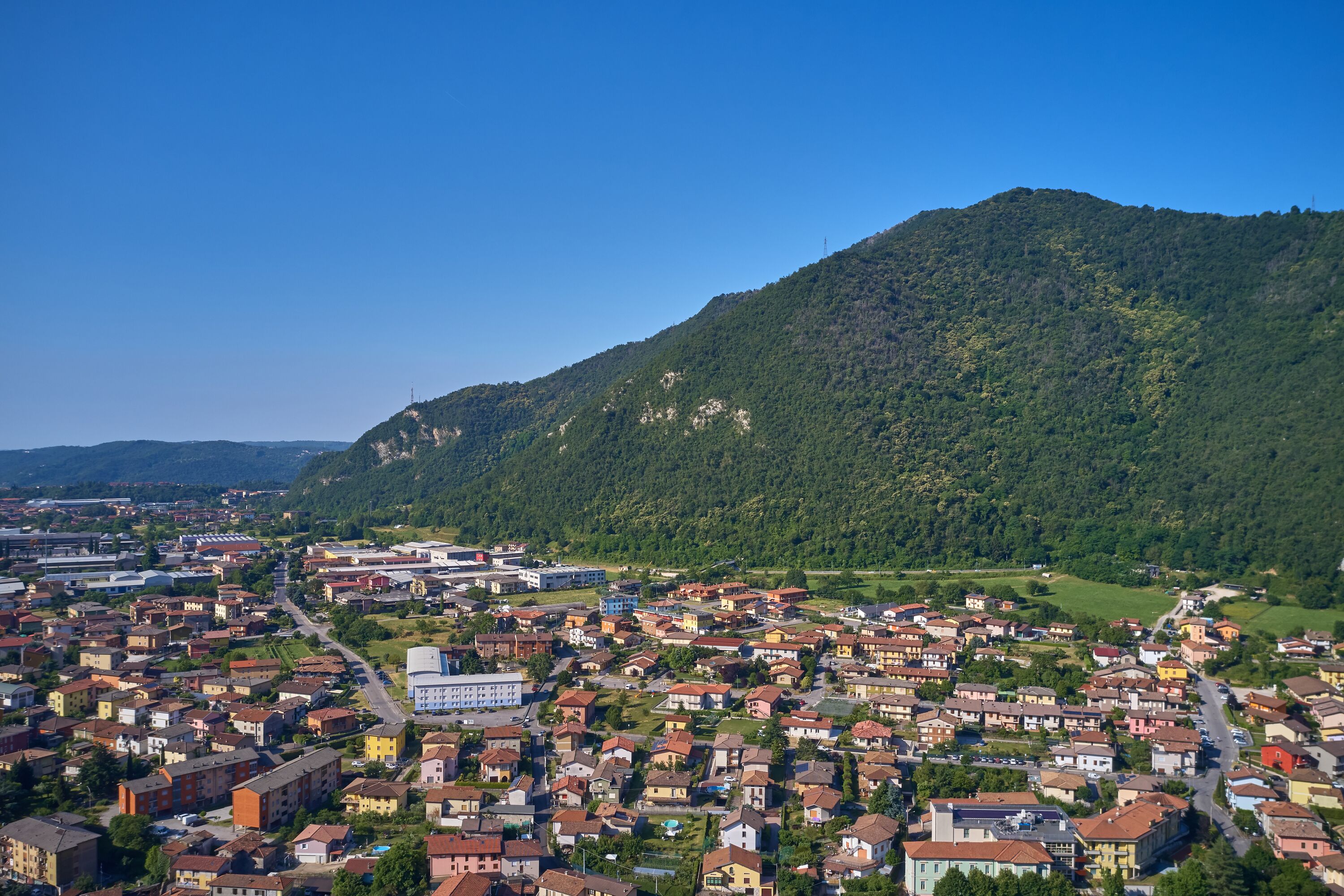 Un pueblo con una mezcla de edificios residenciales y comerciales, rodeado por una montaña.