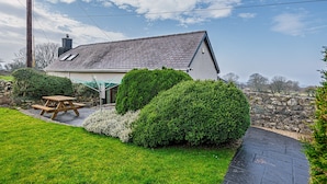 A house with a sloped roof, a stone wall, and a paved driveway. - Fox's Lair Farmhouse - sleeps 6 guests  in 3 bedrooms (Caernarfon)