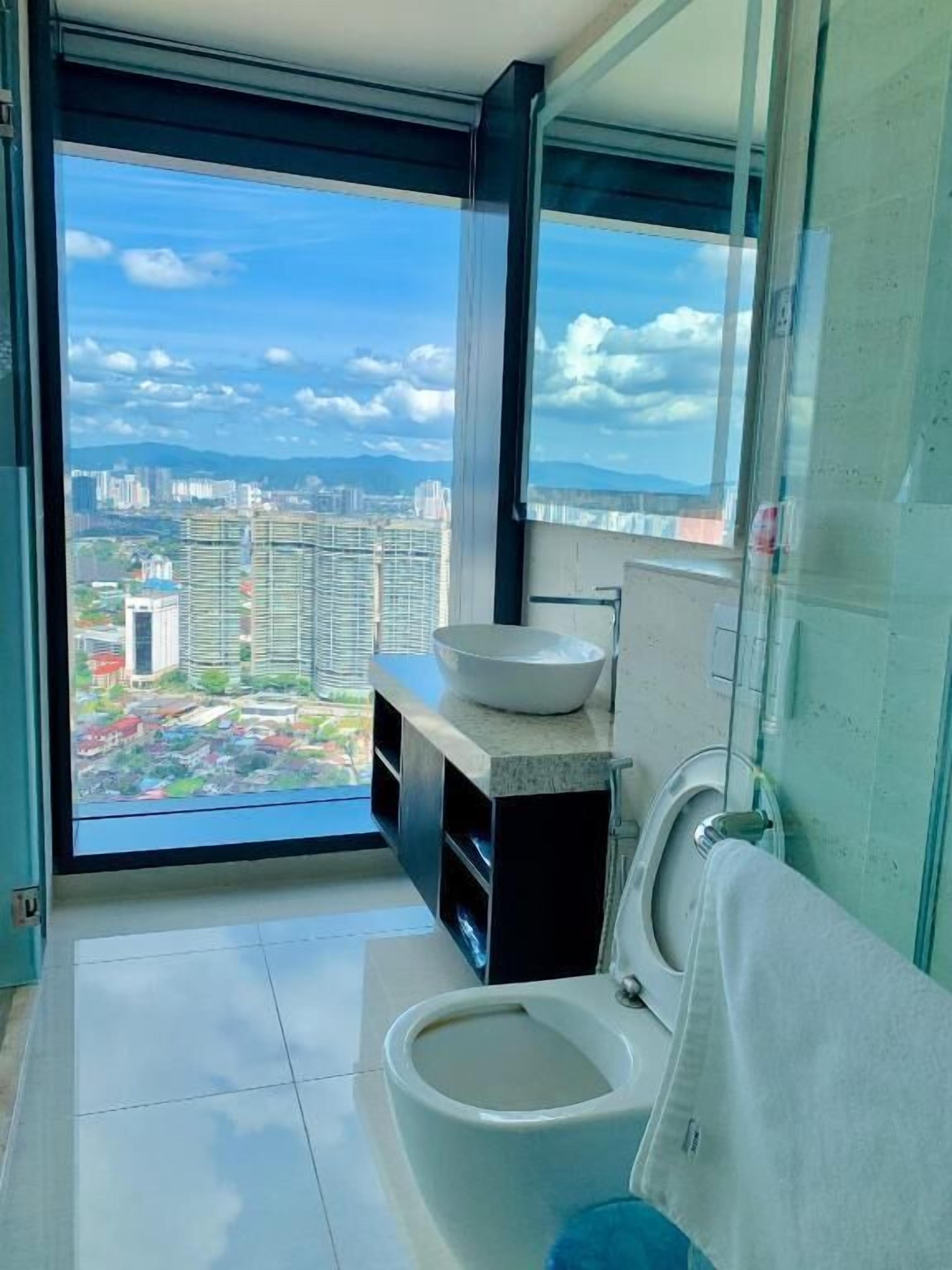A modern bathroom with a large window, a toilet, and a sink.