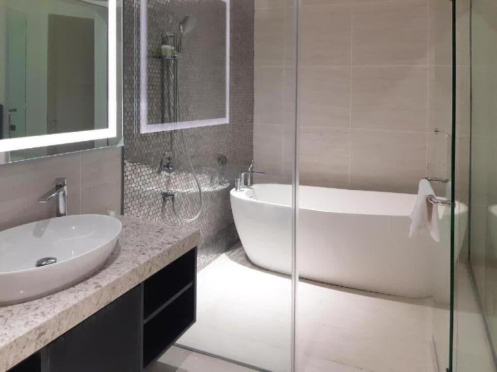 Een moderne badkamer met een vrijstaand bad, een grote spiegel en een wastafelmeubel met een wastafel.