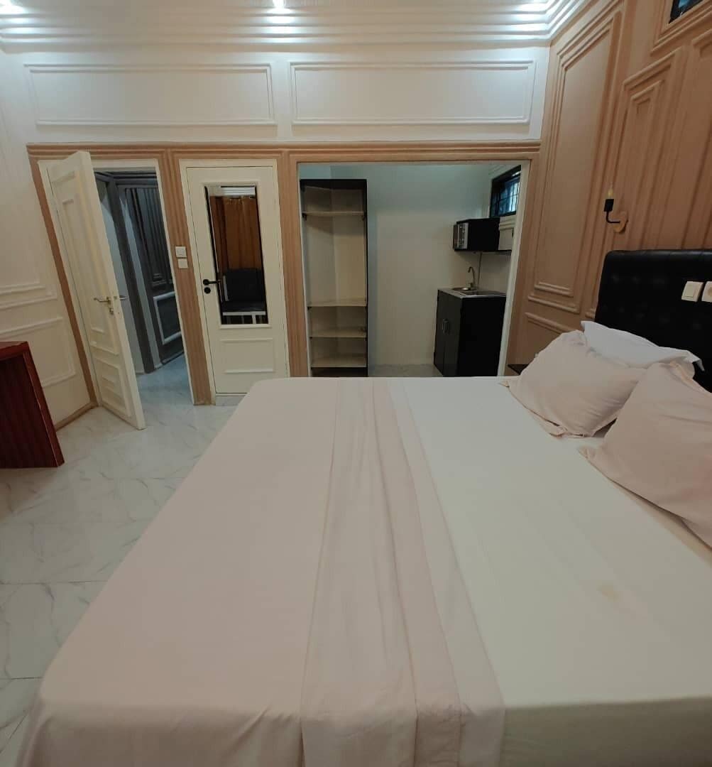 A bedroom with a bed, a wardrobe, a mirror, and a door leading to another room.