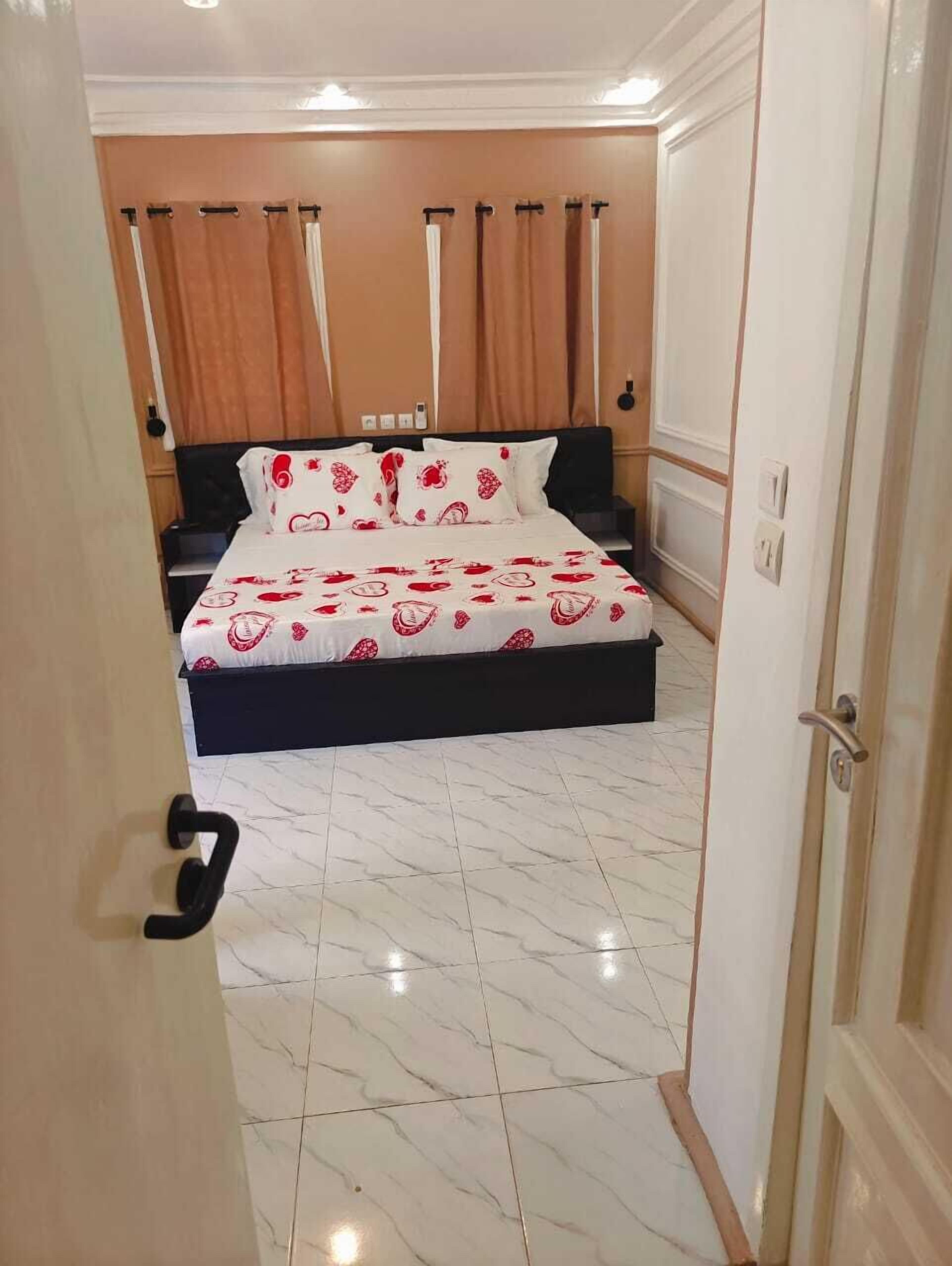 Una camera da letto con un letto, tende, una porta e un pavimento piastrellato.