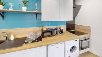 A compact kitchen with a microwave, toaster, sink, and washing machine.