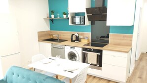 A compact kitchenette with a microwave, stove, and dishwasher. - Apartment 'Cosy Calme Bord De Seine Jardin' with Wi-Fi (Le Mée-sur-Seine)