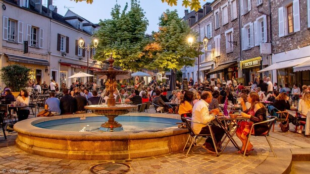 A public square with a fountain, outdoor seating, and surrounding buildings. - Apartment 'Cosy Calme Bord De Seine Jardin' with Wi-Fi (Le Mée-sur-Seine)