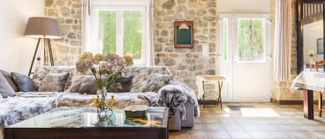 Una sala de estar acogedora con pared de piedra, sofá, mesa de centro y lámpara.