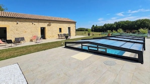 Un bâtiment en pierre doté d’une piscine, d’un espace extérieur aménagé pour s’asseoir et d’un ciel dégagé.