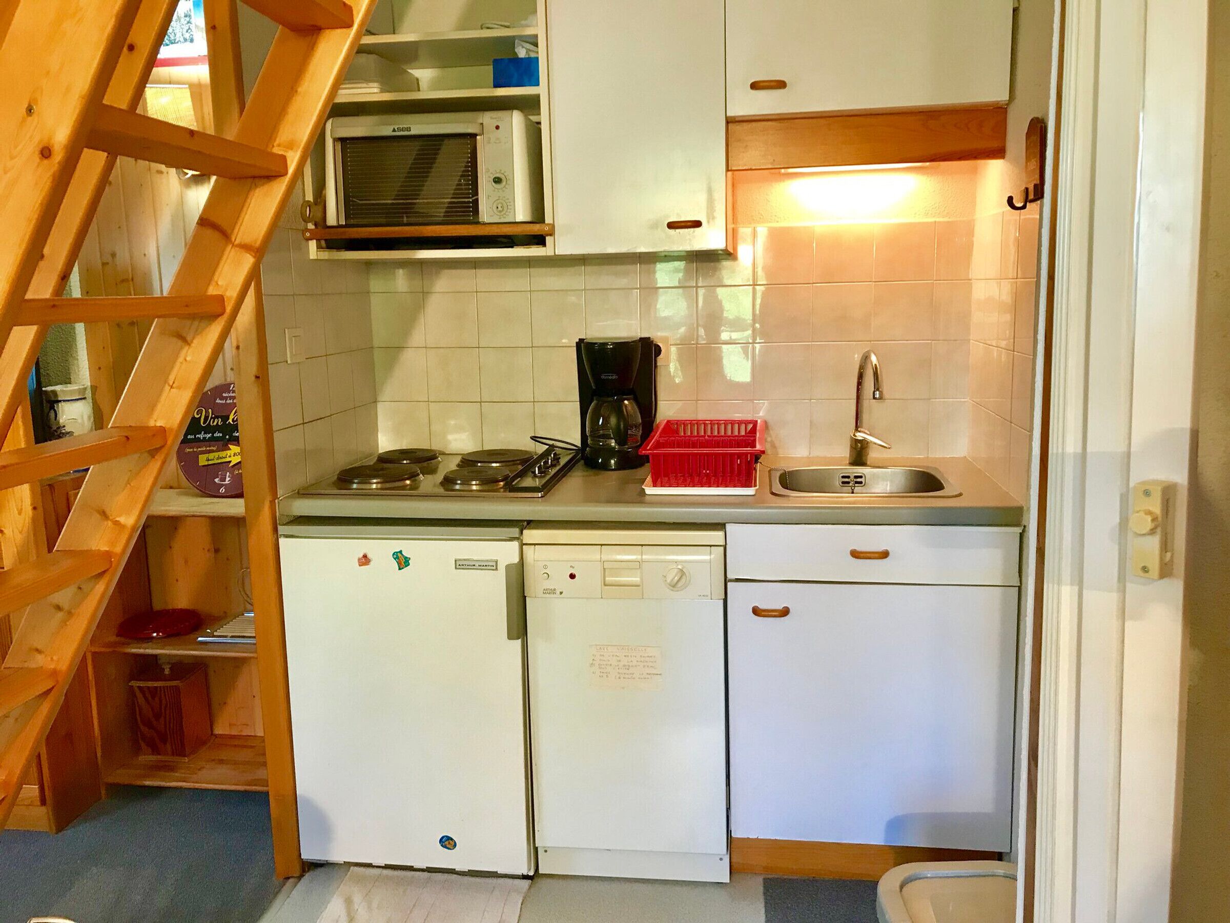 A compact kitchen with a microwave, stove, sink, and dishwasher.