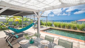 A covered outdoor area with a pool, seating, and a table set for dining.