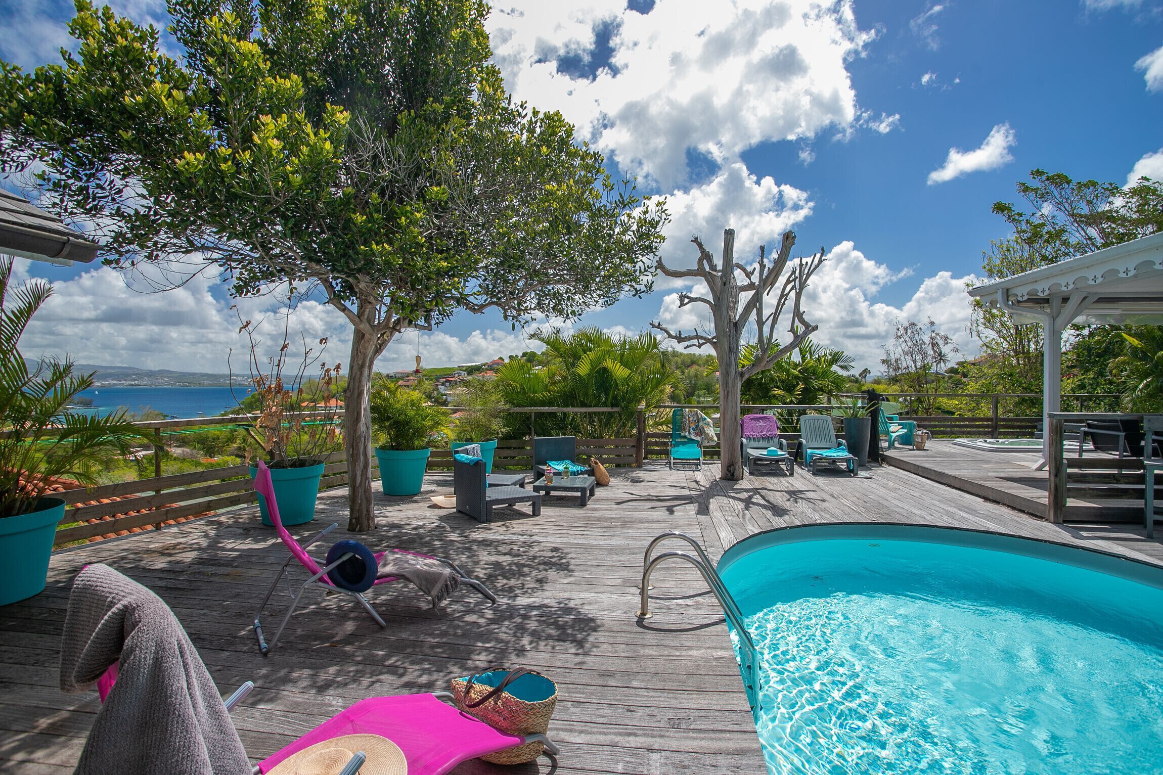 A wooden deck with a pool, lounge chairs, and potted plants.