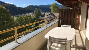 A balcony with a table and chairs, overlooking a town and mountains. - 2-room apartment with balcony and mountain views (Villard-de-Lans)