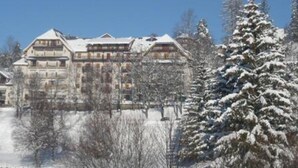 A large, multi-story hotel with a traditional architectural style, surrounded by snow-covered trees and a clear blue sky. - Cozy apartment with balcony and park view in Villard-de-Lans (Villard-de-Lans)