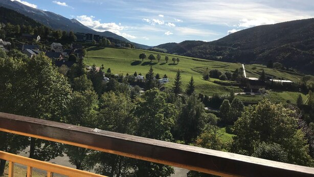 A scenic view of a valley with houses and a church, surrounded by mountains and greenery. - Cozy apartment with balcony and park view in Villard-de-Lans (Villard-de-Lans)