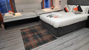 A modern hotel room with two beds, a grey headboard, a plaid rug, and a view of the city at dusk. - Mayfield Suites  (Edinburgh)