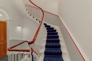 Een trap met witte leuningen en tredes bekleed met blauw tapijt.