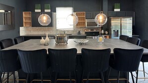 Una cocina moderna con una isla central, sillas negras e iluminación colgante.