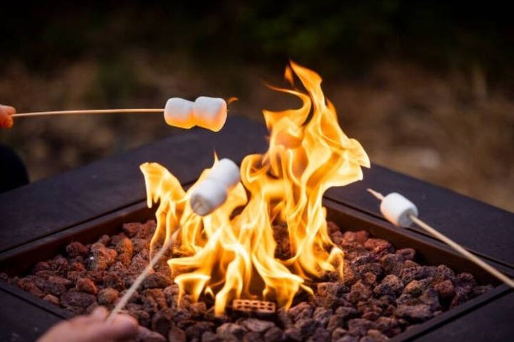 A fire pit with marshmallows being roasted over the flames.