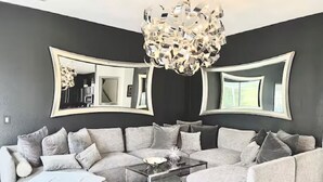 Una sala moderna con un sofá modular, una mesa de centro de vidrio y una lámpara de techo original.