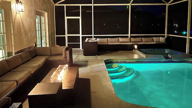 Un área de piscina al aire libre con un jacuzzi, un sofá y una mesa.